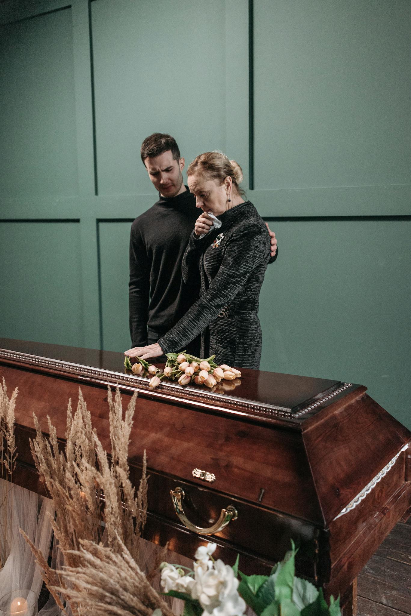 A touching moment between family members at a funeral, expressing sorrow and loss.